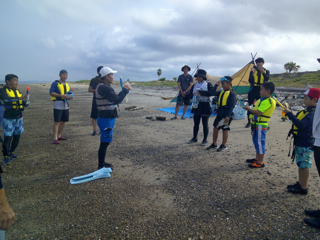 スノーケリング体験の準備をする親子6名の参加者と指導スタッフ