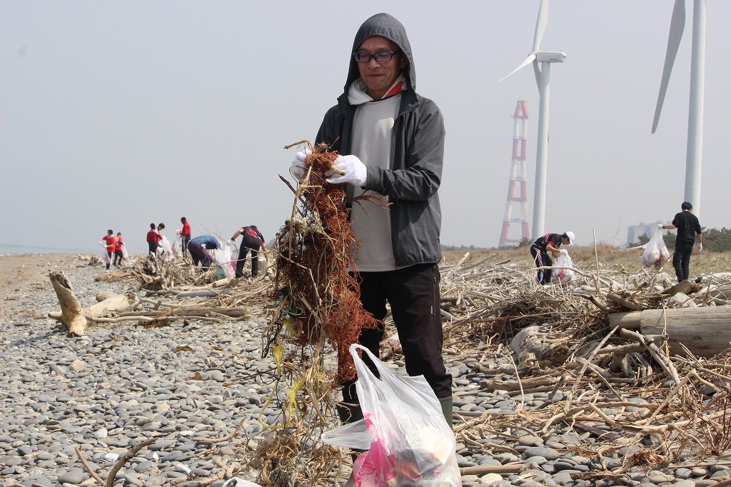 流木の間に挟まったゴミを丁寧に回収