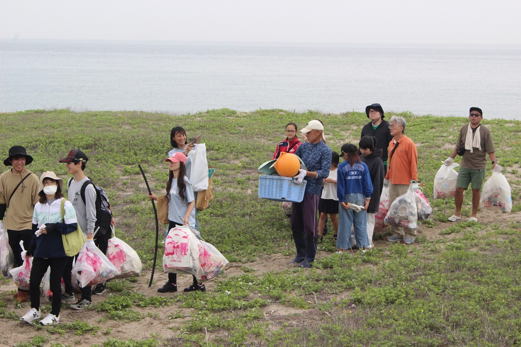 上流域から流れ着いたゴミについて説明を受ける参加者たち