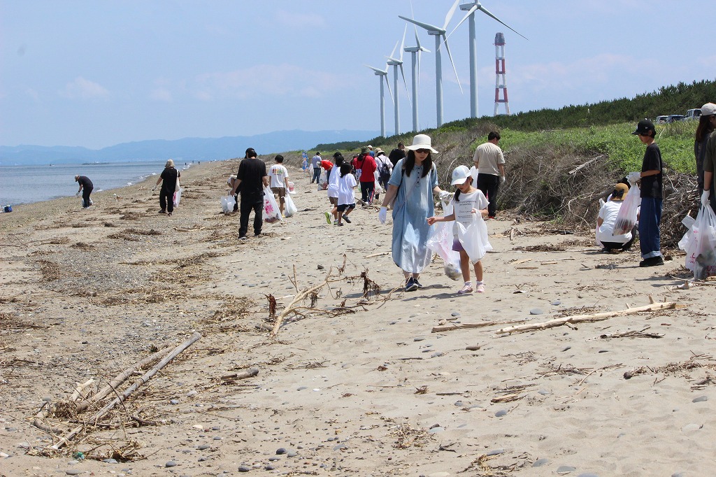 小さな容器に入ったヒラメの稚魚を優しく海に送り出す子どもたち
